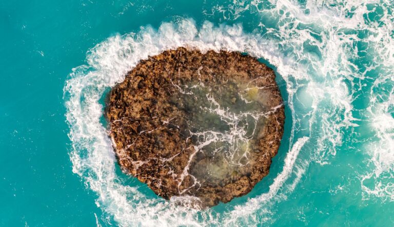 Stunning aerial capture of a circular rocky formation in Bermuda's turquoise ocean waters.